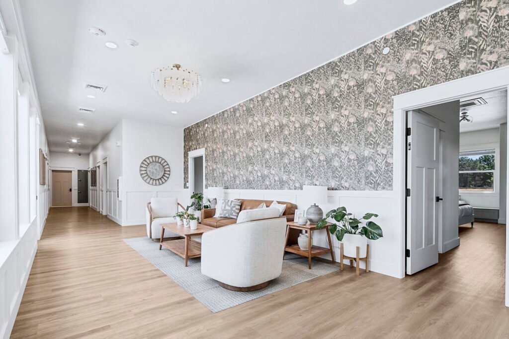 Bright living room with floral accent wallpaper, a leather sofa and white swivel chairs at The Ponderosa Estate