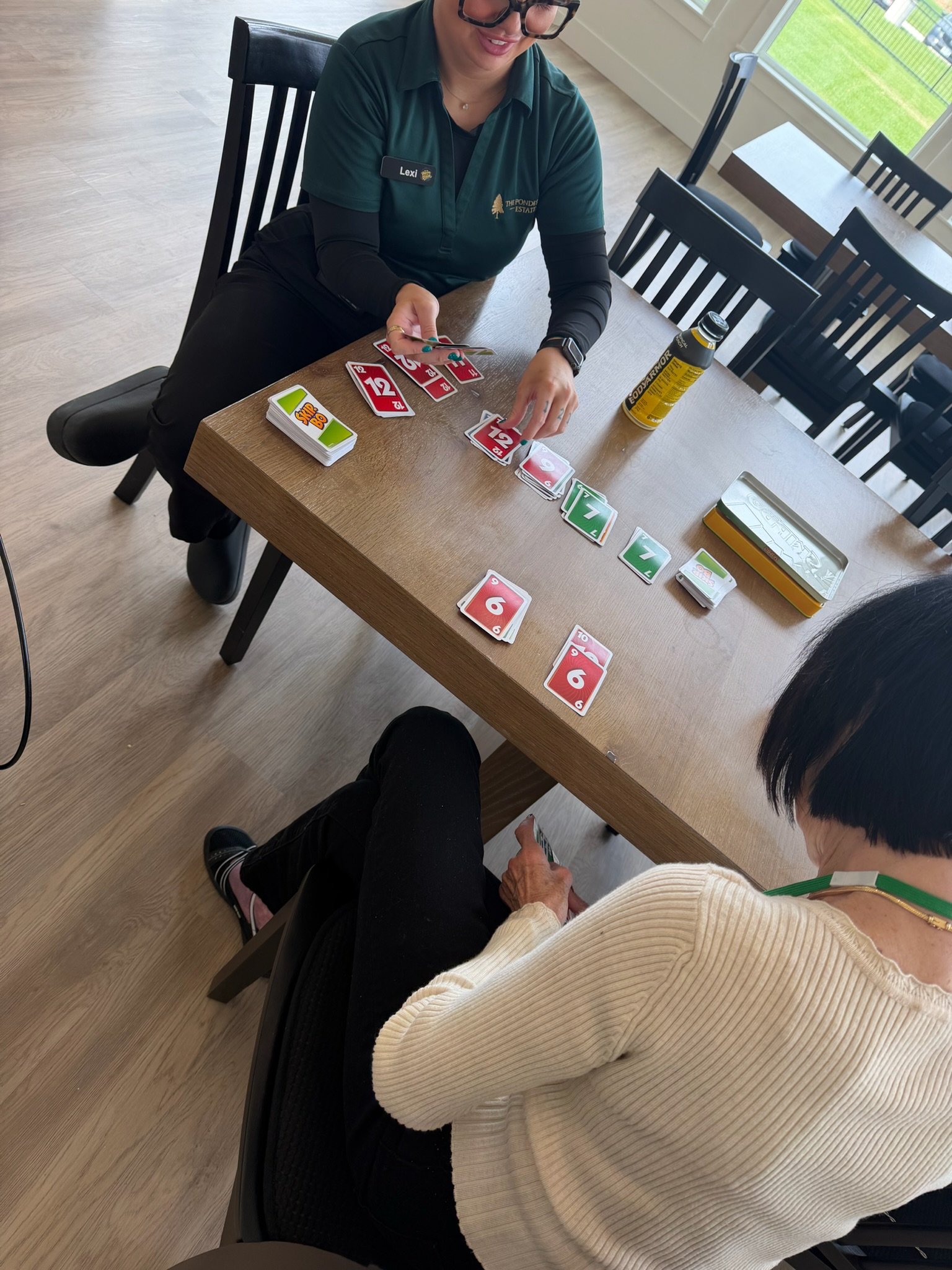 A caregiver playing a card game with a Resident at The Ponderosa Estate