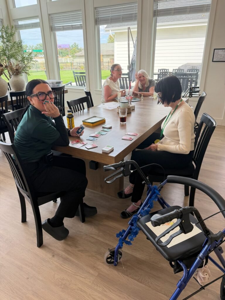 Residents and caregivers sharing a laugh over a card game at the dining table at The Ponderosa Estate in Eagle, Idaho