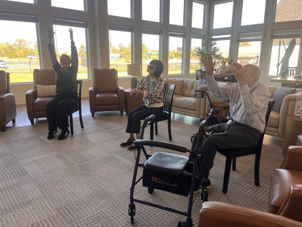 Residents taking part in a seated chair exercise class in the sunlit lounge at The Ponderosa Estate in Eagle, Idaho